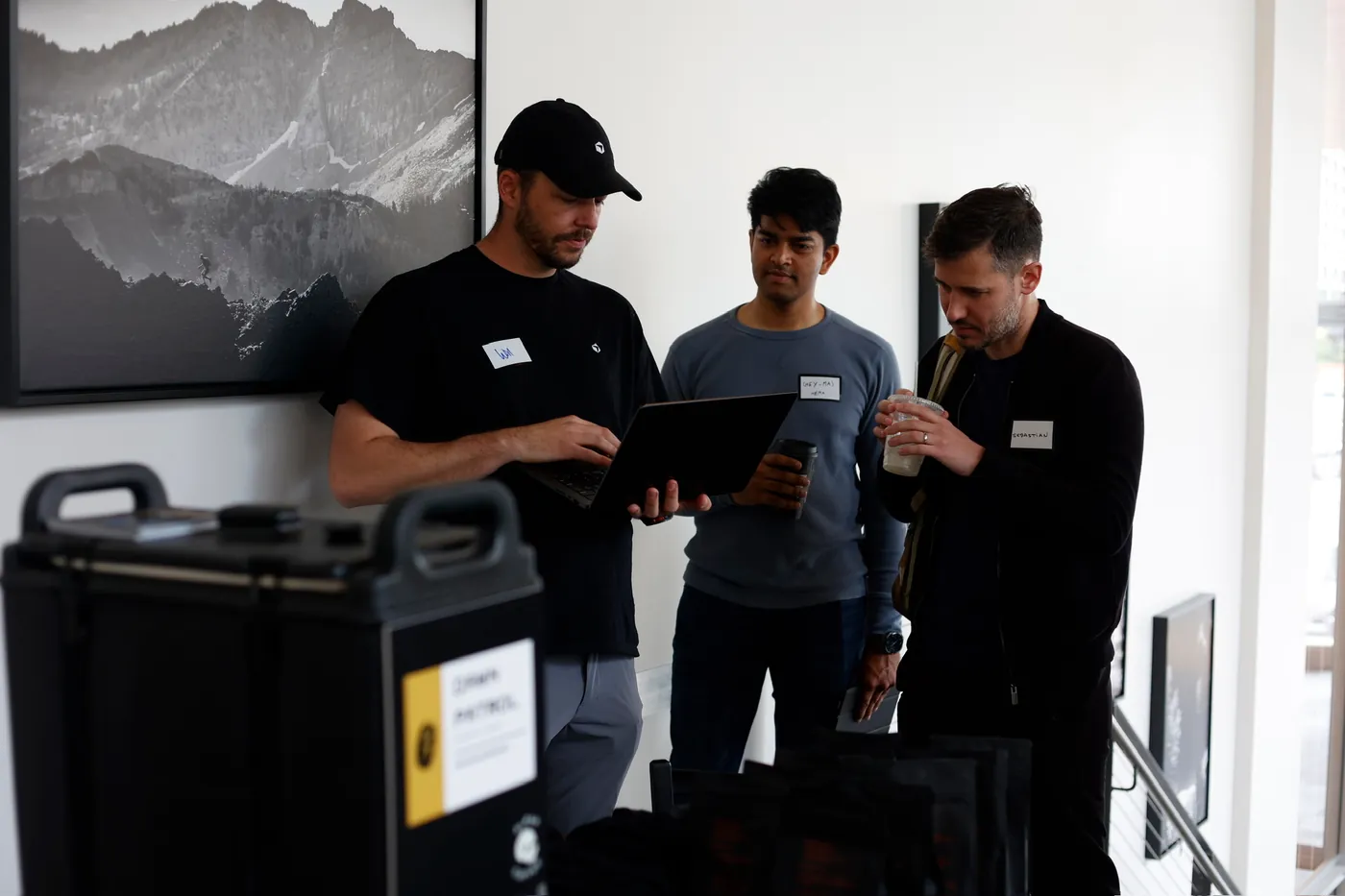 Will Rowston showing a laptop to two attendees at a Cursor event